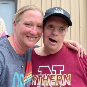 female direct support worker smiling and hugging smiling man with disbilities