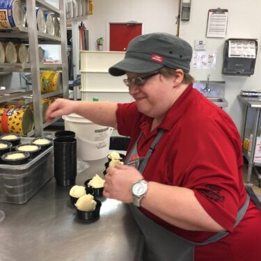 female client working in kitchen with supported employment